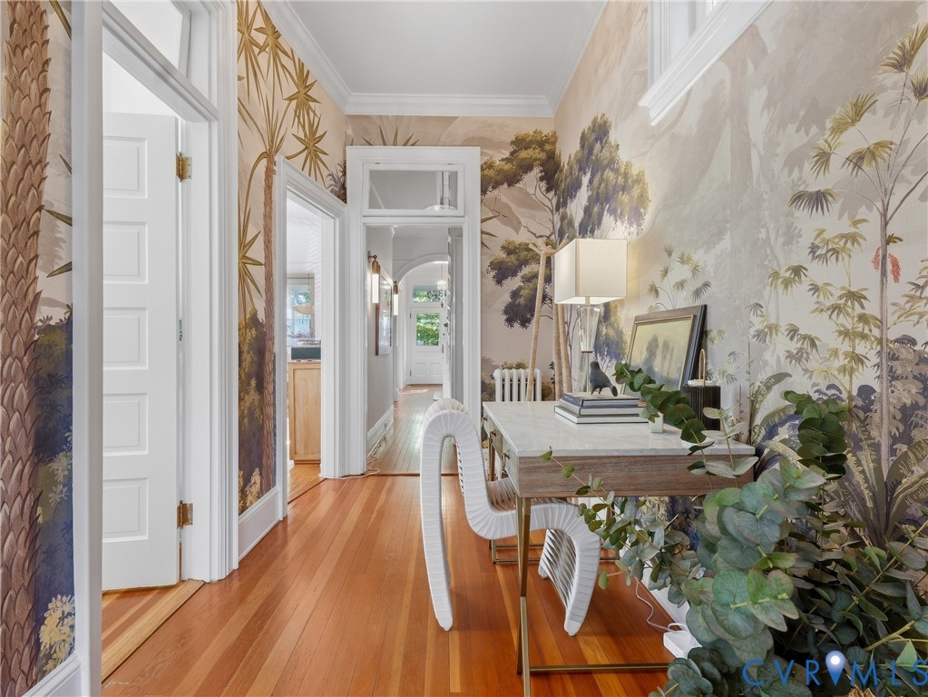 Hardwood flooring, decorative wall coverings, white trim, and crown molding