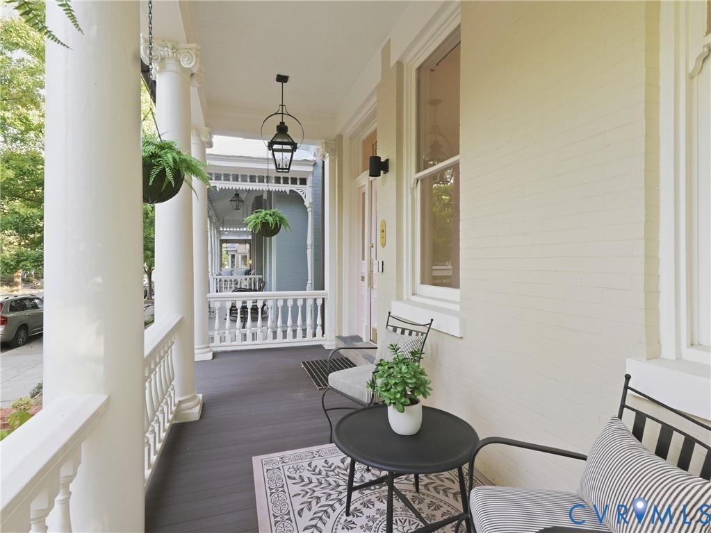 Expansive front porch featuring white columns with decorative capitals, balustrade railing, and Trex flooring.