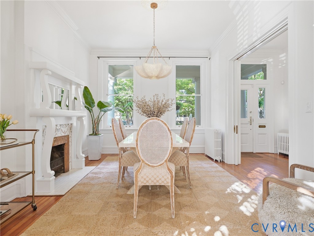 Hardwood flooring, decorative fireplace with an ornate mantel, crown molding, and custom chandelier lighting fixture