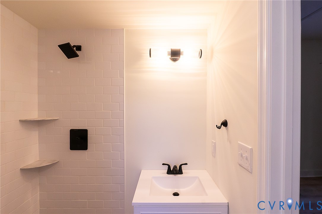 White subway tile shower with two built-in corner shelves and a matte black rain shower head