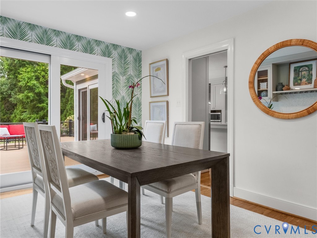 Sliding glass doors to outdoor deck, recessed lighting, wood-finish flooring, pocket door to kitchen, and decorative wall paneling
