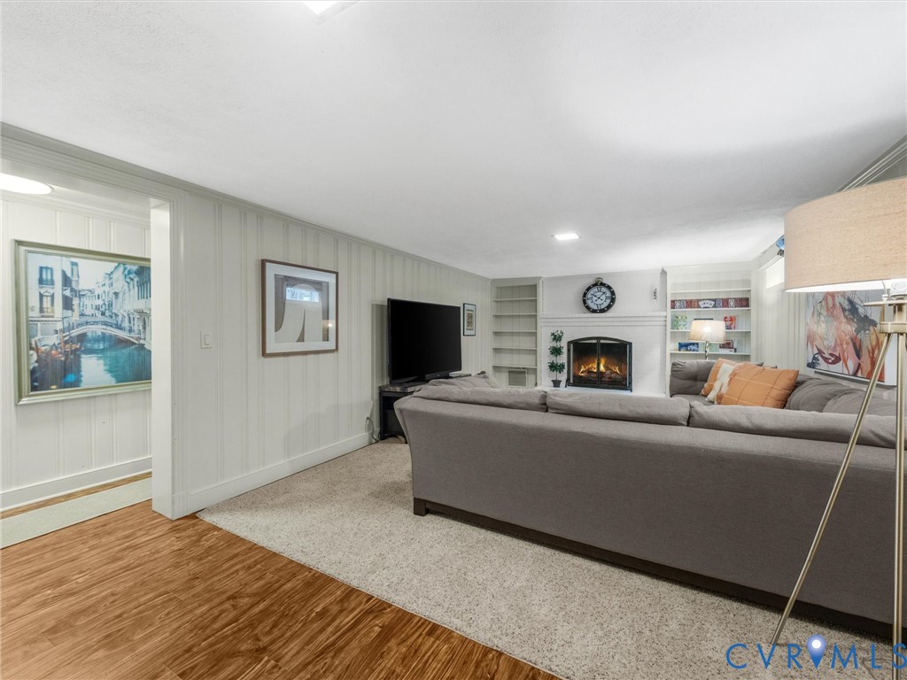 Recessed lighting, fireplace with a white mantel, built-in shelving, carpeted flooring, and wood-finish flooring