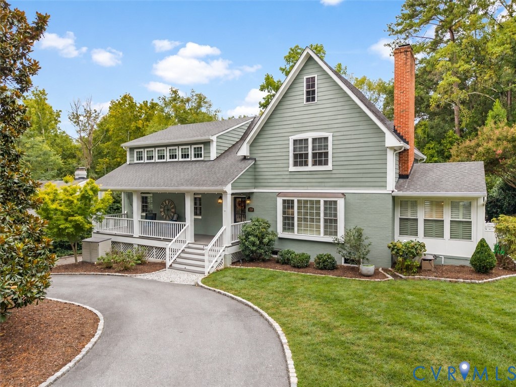 Expansive front exterior featuring a covered porch with white railings, a prominent brick chimney, and a bay window