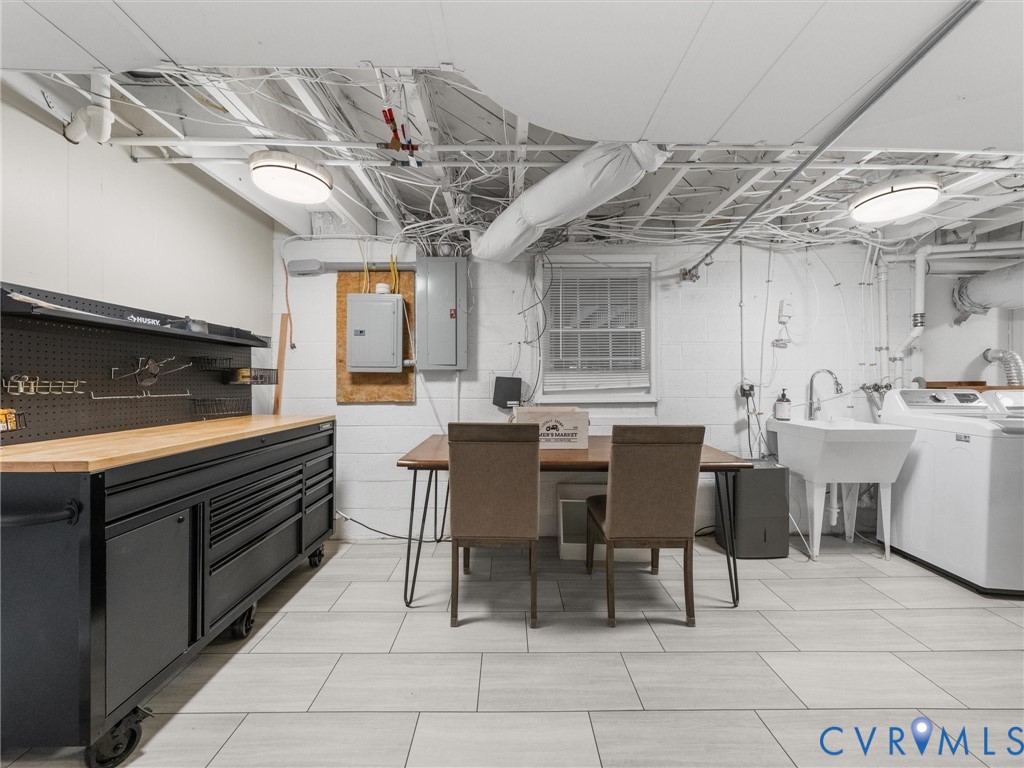 Utility space featuring light-toned flooring, exposed ceiling joists, and a utility sink