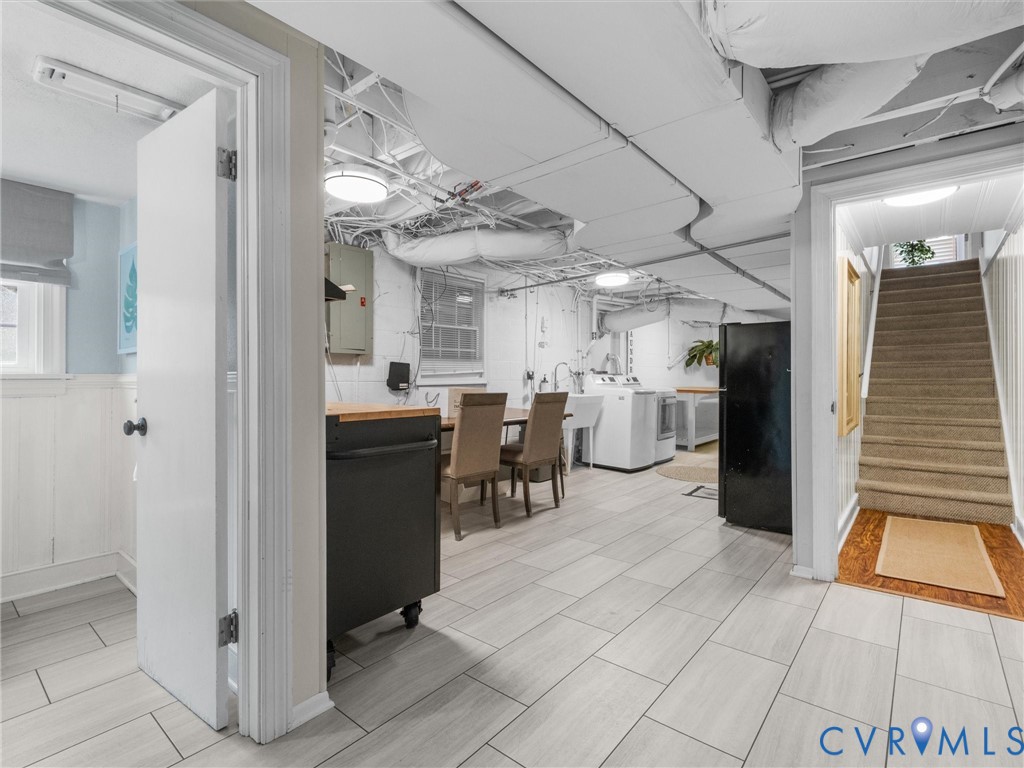 Light-toned tile flooring, exposed ductwork, utility sink, washer, and dryer
