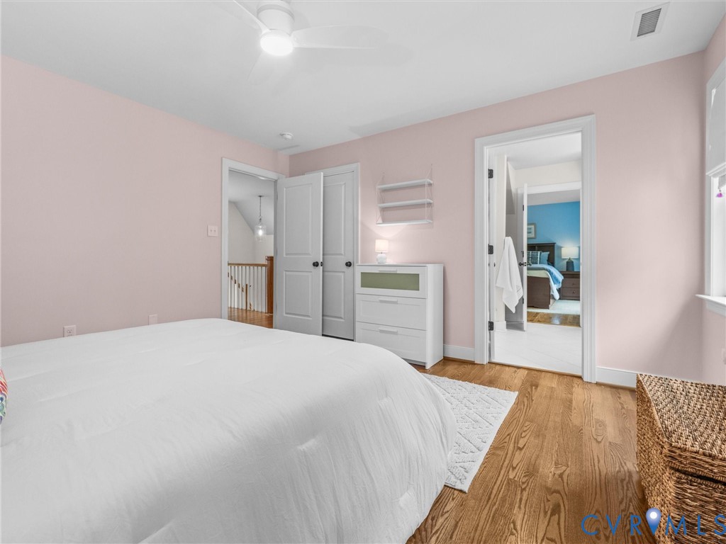 Wood-finish flooring, white trim, and a ceiling fan with integrated lighting
