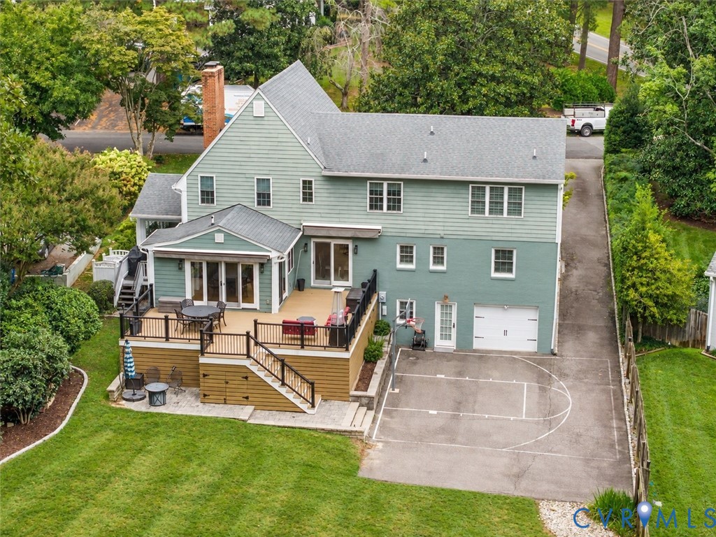 Multi-level rear deck with dark railings, direct access to a bonus room, and a paved sport court