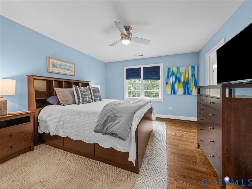 Hardwood flooring, painted walls, ceiling fan with integrated lighting, window with blinds, and a built-in closet