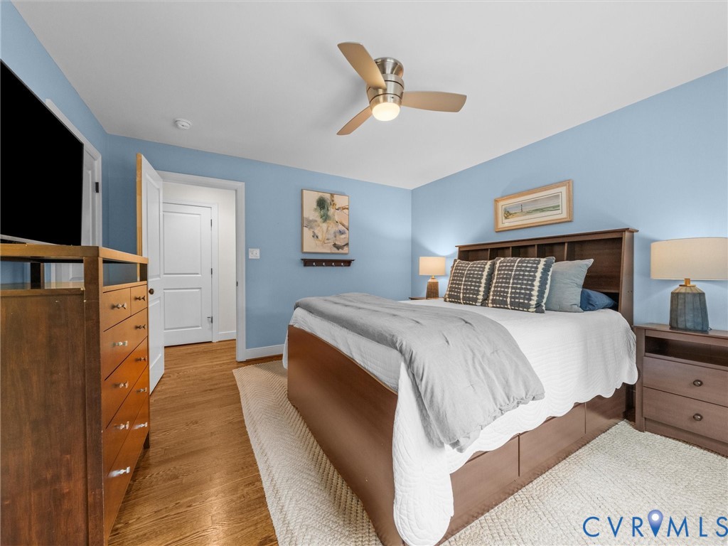 Wood-finish flooring, overhead ceiling fan with integrated lighting, and white trim throughout