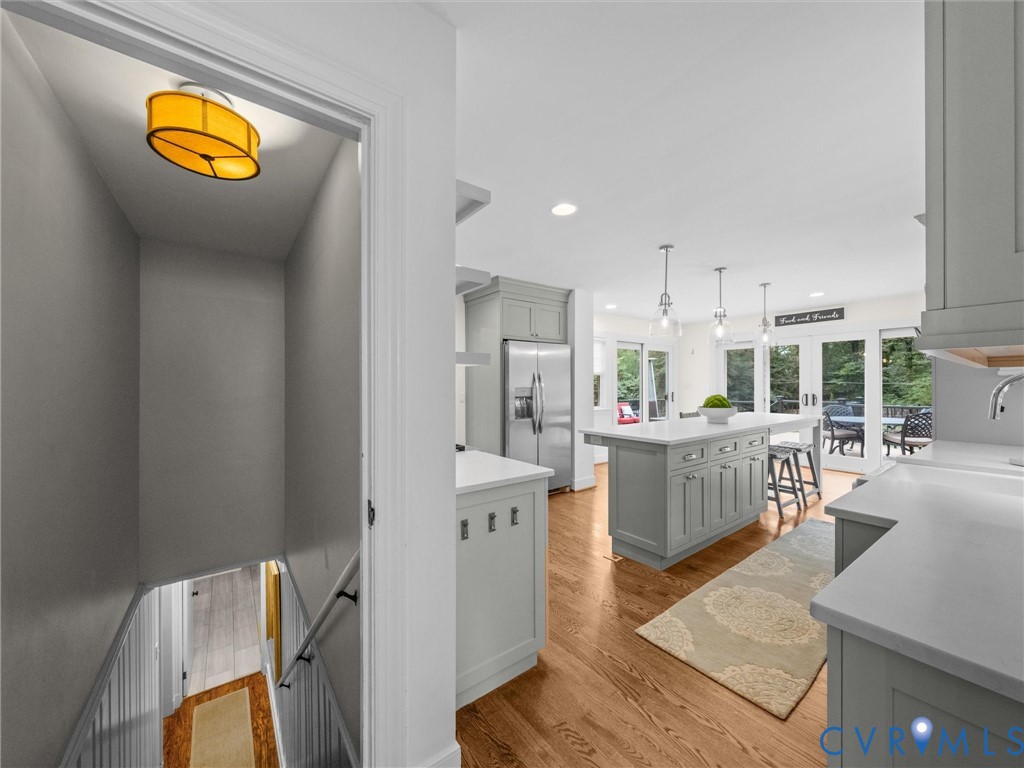 Recessed lighting, wood-finish flooring, light gray cabinetry, stainless steel appliances, and French doors leading to exterior space