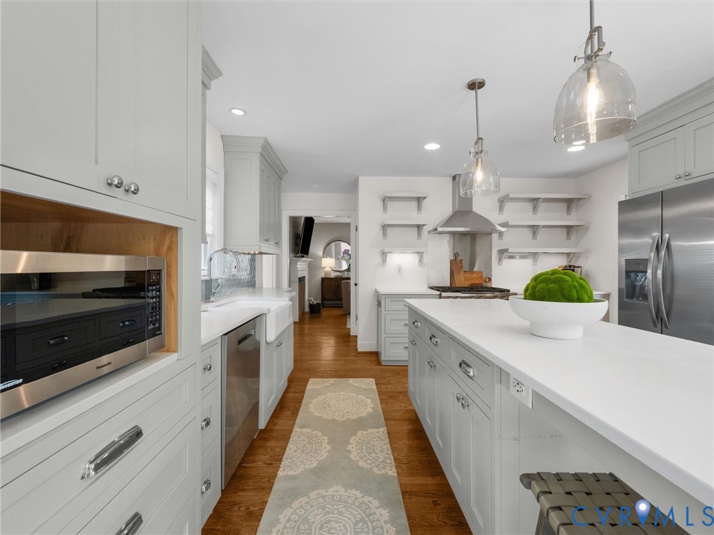 Well-appointed kitchen featuring light-toned cabinetry, a spacious center island with a light-toned countertop, stainless steel appliances, and wood-finish flooring