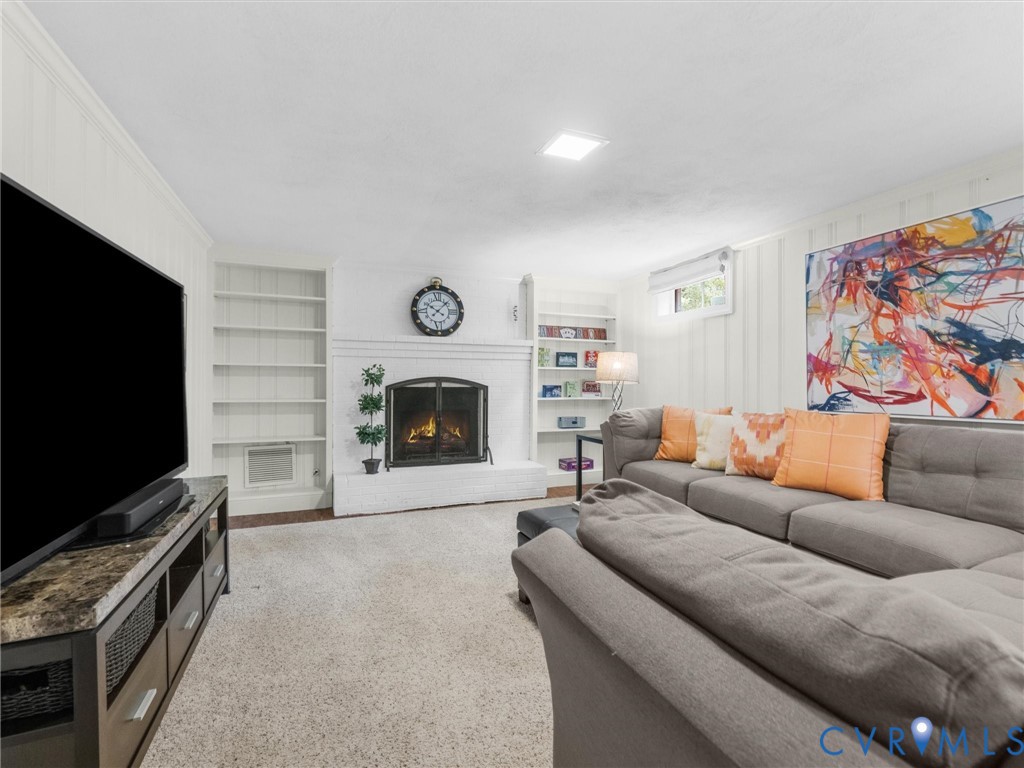 Built-in shelving, fireplace, recessed lighting, and wall paneling