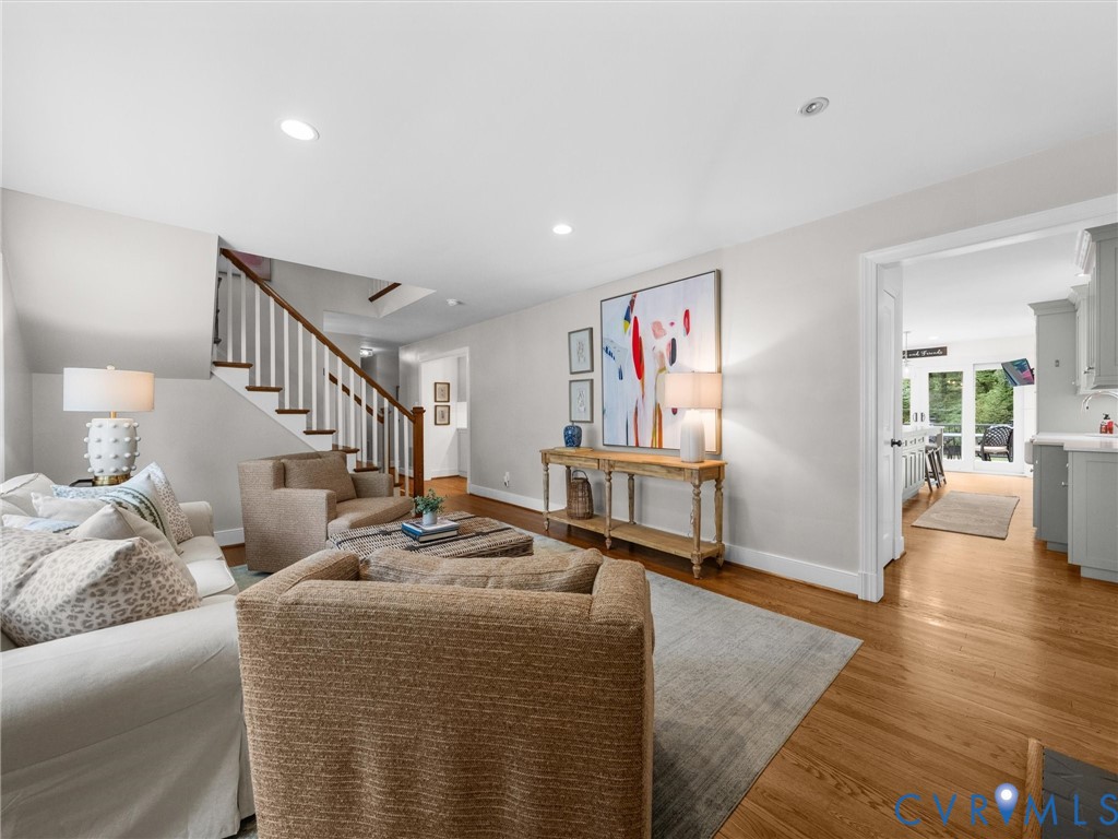 Hardwood flooring, recessed lighting, white trim, open doorway, and a staircase with wood treads and white risers