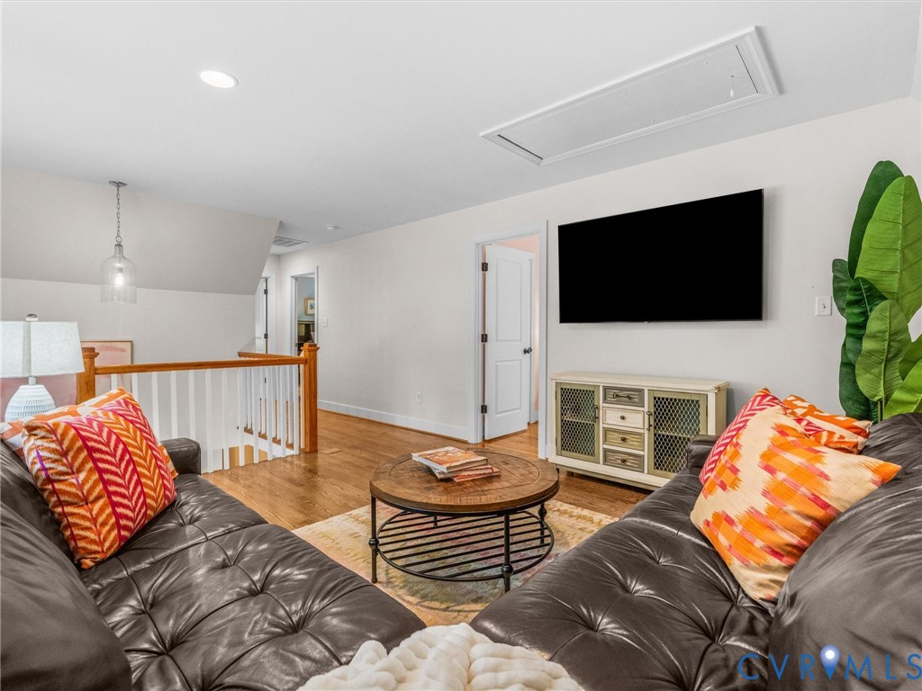 Hardwood flooring, white painted railings, recessed lighting, and a contemporary pendant light fixture