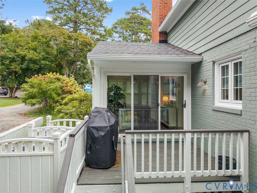 Deck with white railings, sliding glass door, and exterior brick finish