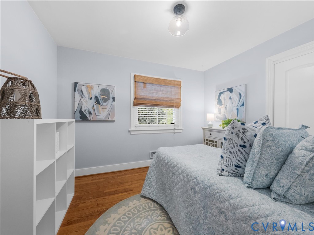 Hardwood flooring, single window with blinds, surface-mount ceiling light fixture, white interior door, and built-in shelving unit