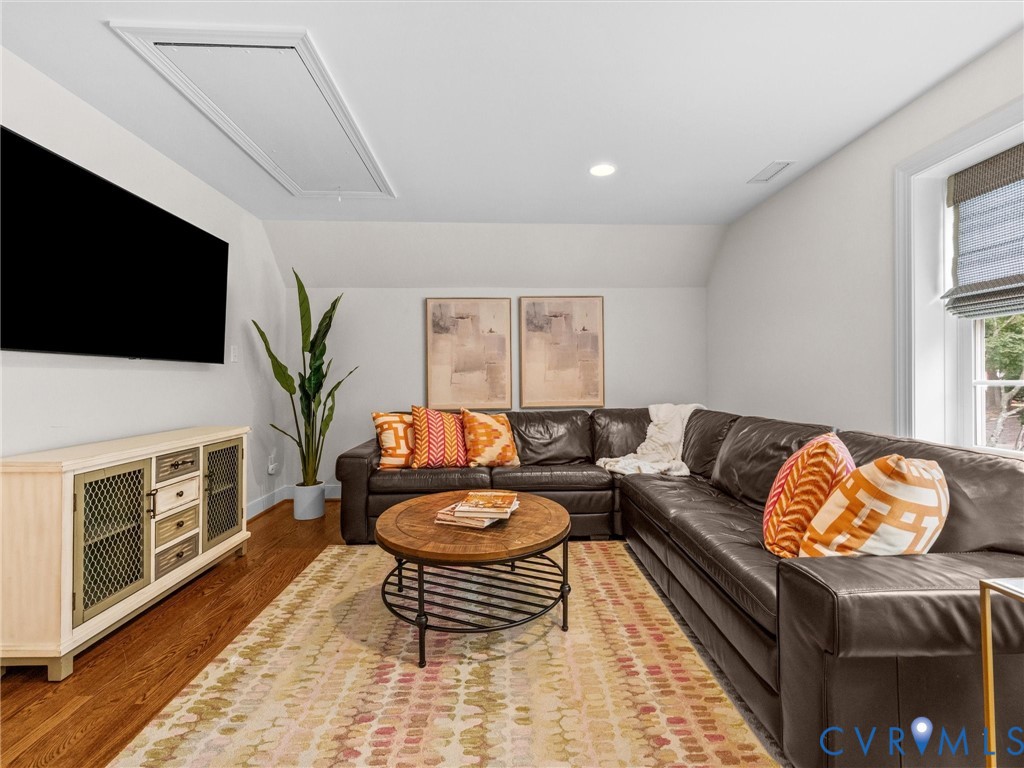 Hardwood flooring, recessed ceiling lighting, sloped ceiling, and a window with blinds