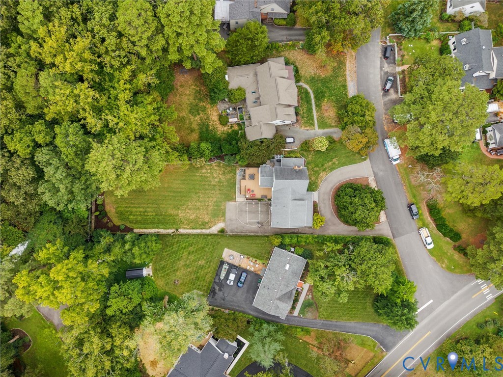 Aerial perspective of the property and surrounding residential area, featuring mature trees, landscaped grounds, and paved roadways