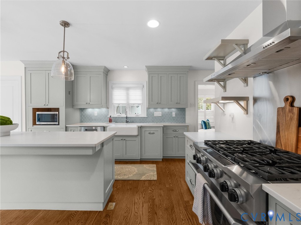 Gourmet kitchen with wood-finish flooring, light gray cabinetry, stainless steel appliances, and white countertops