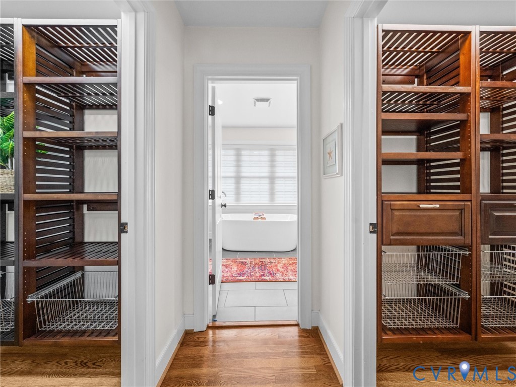 Wood-finish flooring leading to a bathroom featuring a freestanding tub and tiled floor