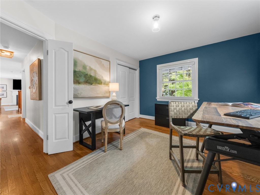 Hardwood flooring throughout, white trim, single window with blinds, overhead lighting, and a closet with a sliding door