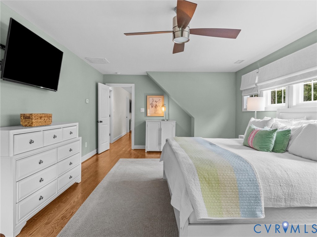 Recessed ceiling fan with wood-finish blades, wood-finish flooring, and white trim windows