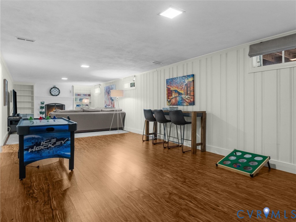 Recessed lighting, wood-finish flooring, fireplace with white mantel, built-in shelving, and board-and-batten wall detailing