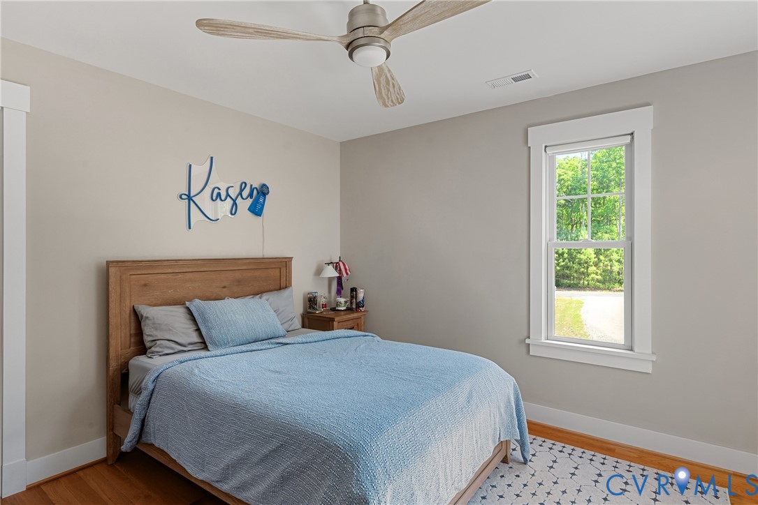 Neutral wall color, wood-finish flooring, white trim detailing, ceiling fan, and a double-hung window