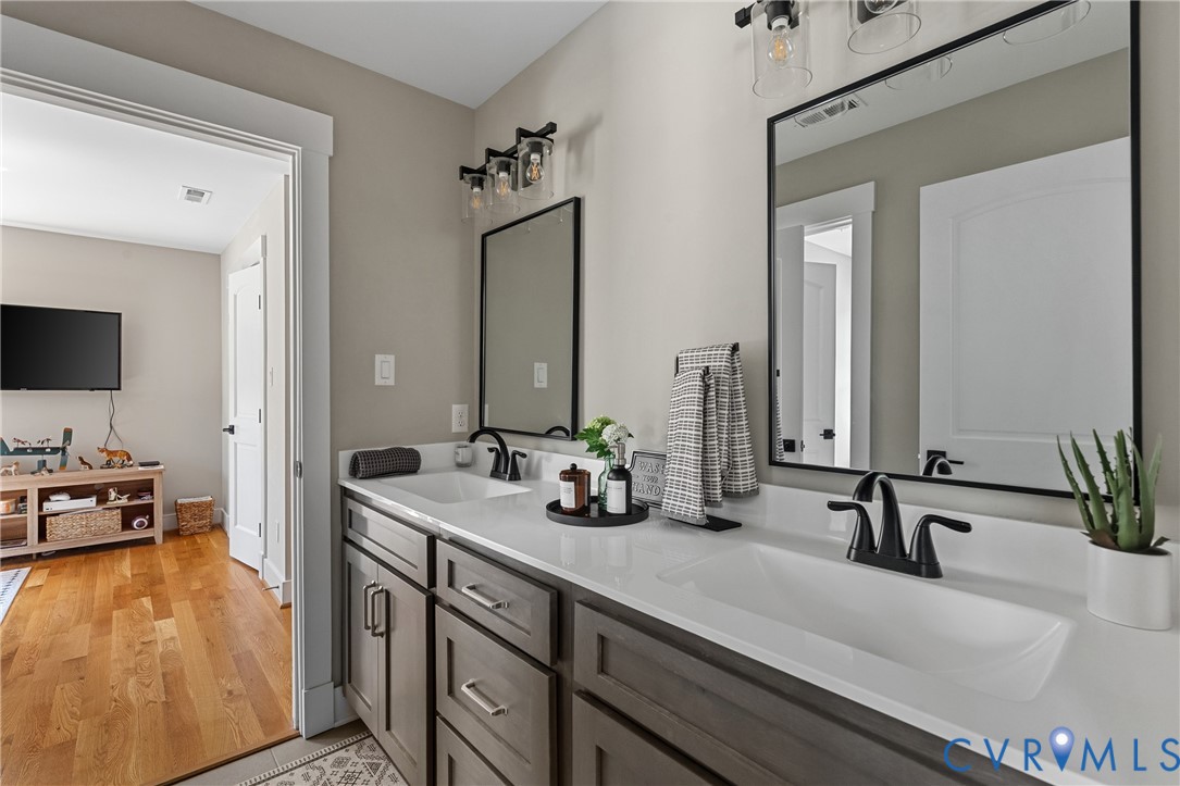 Double vanity with integrated sinks, dark wood-finish cabinetry, contemporary matte black faucets, and rectangular framed mirrors