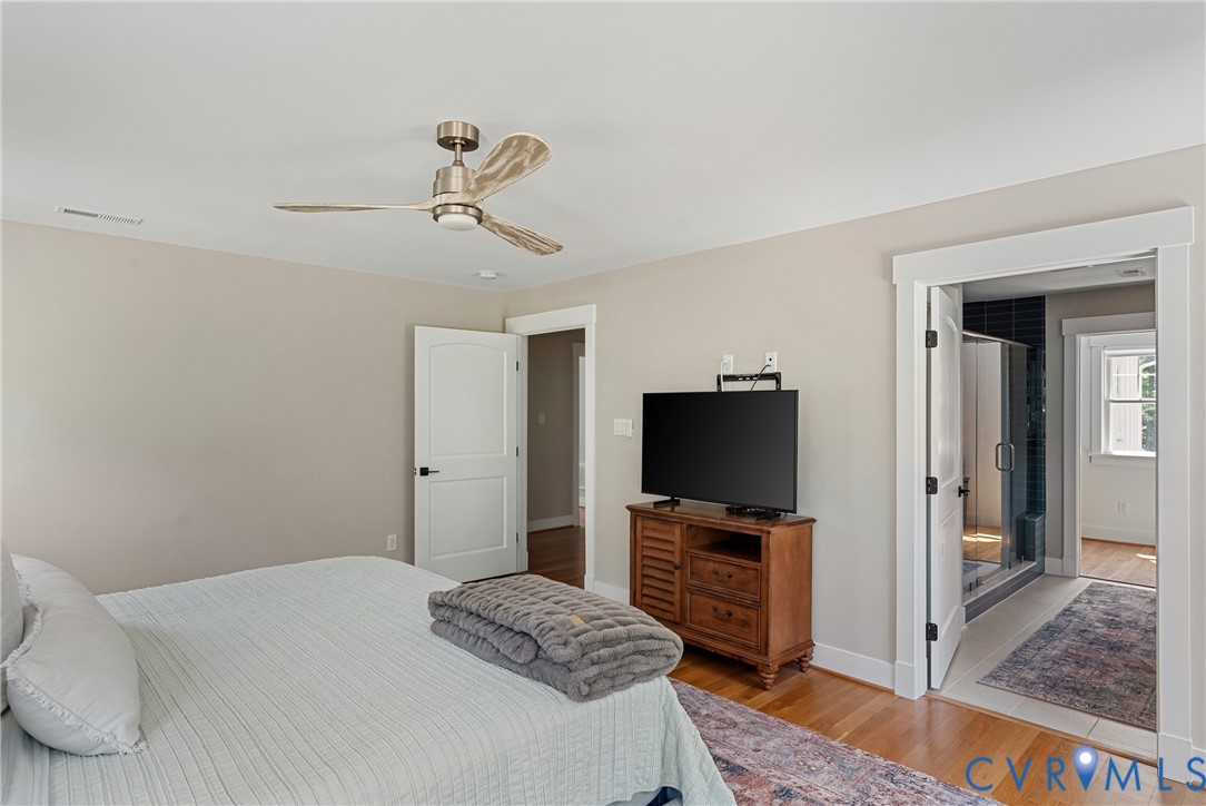 Wood-finish flooring, ceiling fan with brushed nickel accents, and a wide cased opening