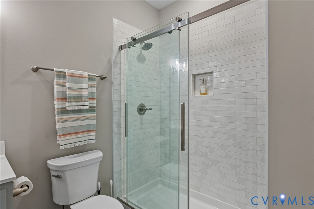 Glass-enclosed shower with a sliding door, subway tile surround, built-in shower niche, and a rain showerhead