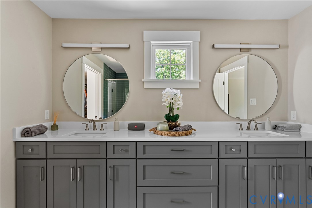 Double vanity with gray shaker cabinetry, integrated rectangular sinks, and surface-mounted circular mirrors