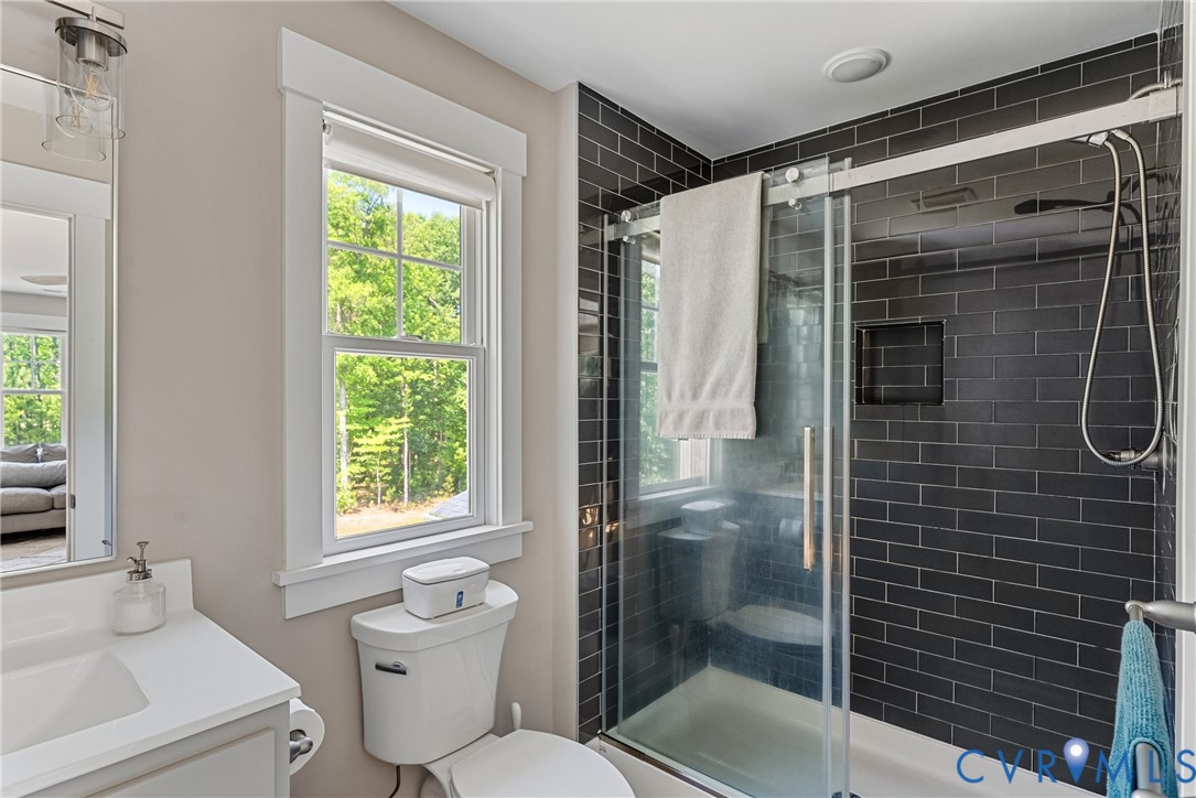 Glass-enclosed shower with dark subway tile, recessed shower niche, and a sliding glass door