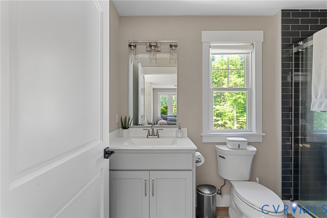 Bathroom featuring a single vanity with a white countertop, chrome faucet, wall-mounted mirror, and a window with white trim