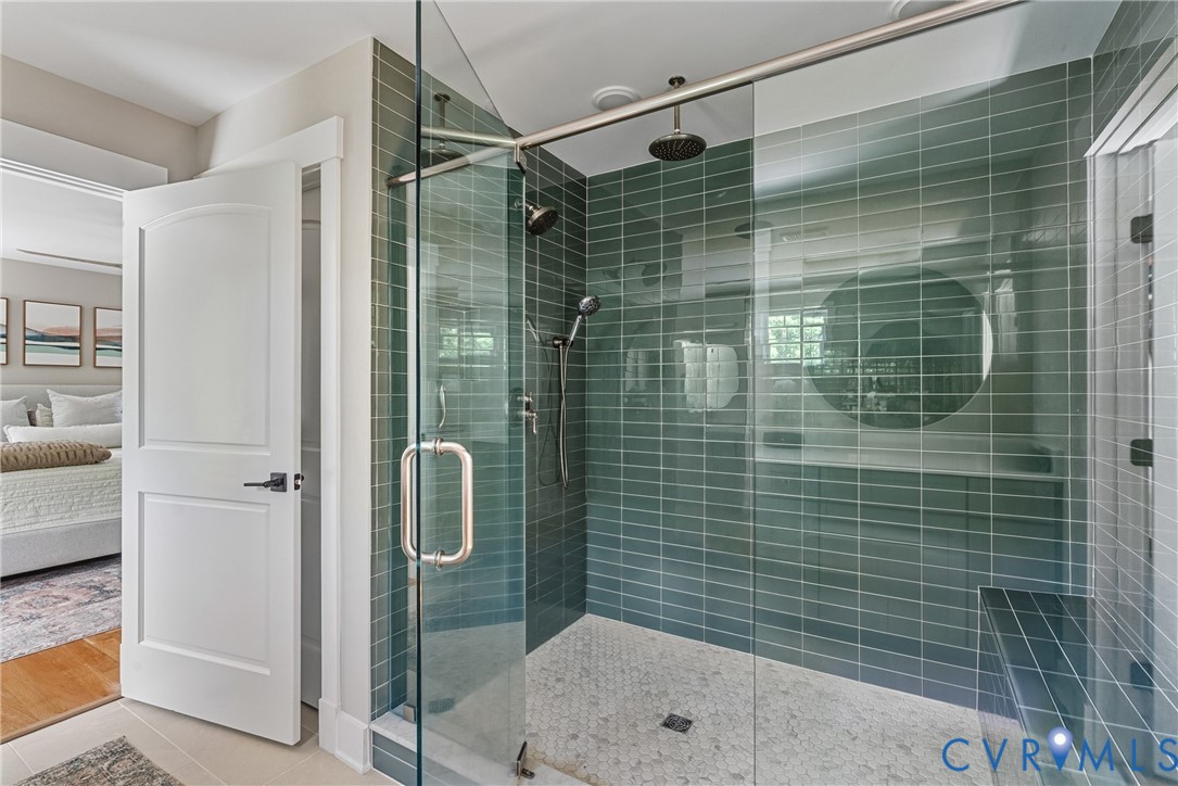 Glass-enclosed shower with horizontal tile walls, a built-in bench, and a rainfall showerhead