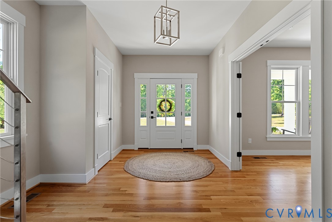 Entryway featuring wood flooring, a transom window over the main door, and a modern geometric pendant light fixture