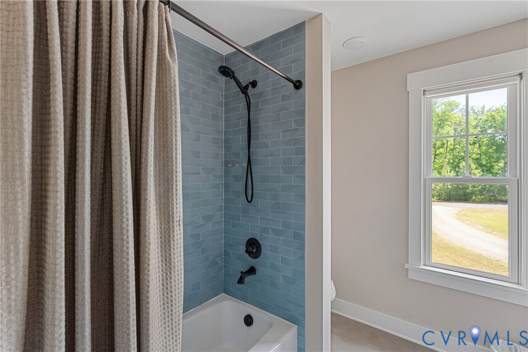 Bathtub and shower combination featuring blue subway tile surround and matte black fixtures
