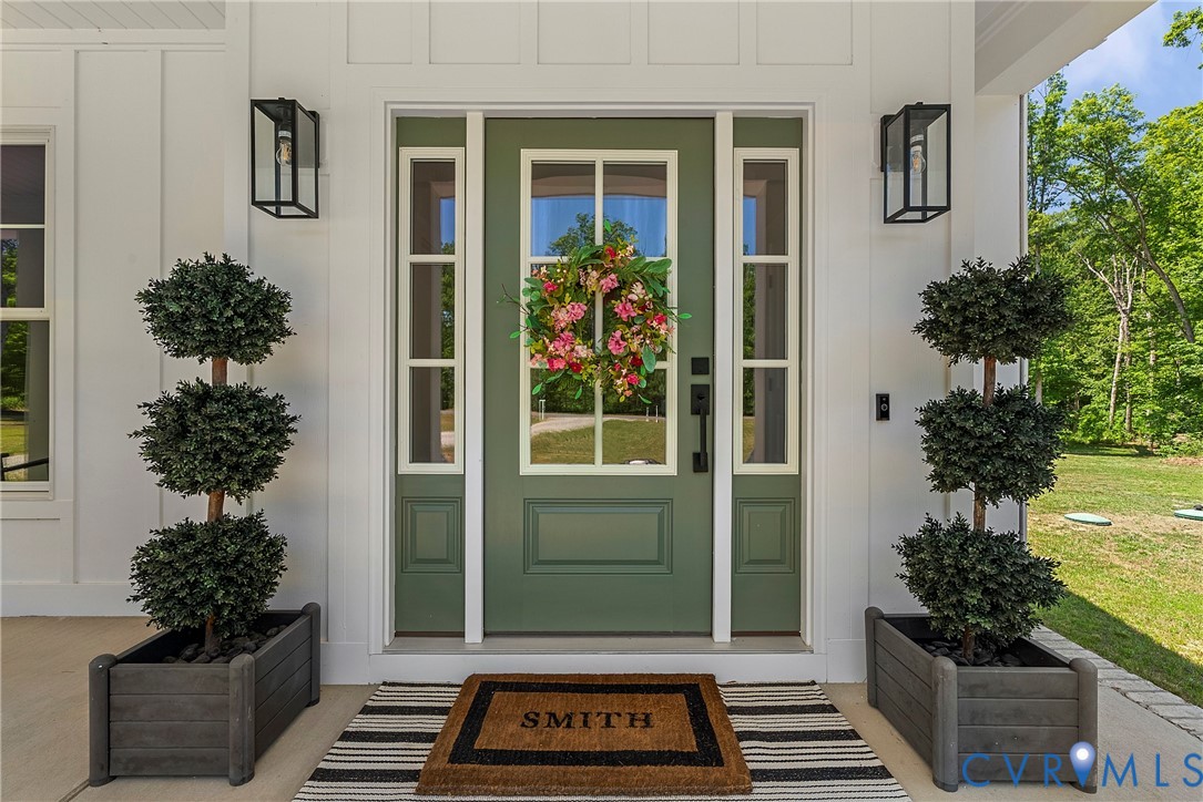 Front entrance with a green panel door, clear glass transom, and sidelights