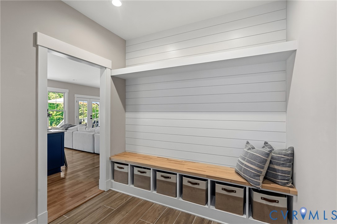 Built-in storage bench with wood top, open shelving, and shiplap-style wall