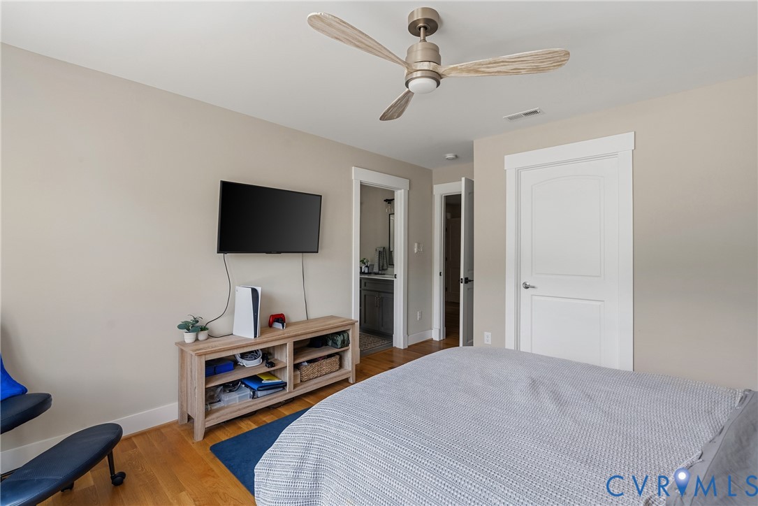 Wood-finish flooring, ceiling fan with integrated lighting, flat-panel interior doors, and neutral wall tones