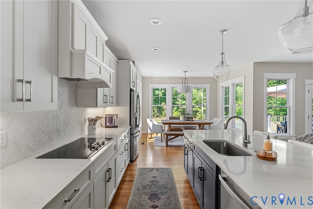 Spacious kitchen featuring white cabinetry, light countertops, wood-finish flooring, and an integrated cooktop