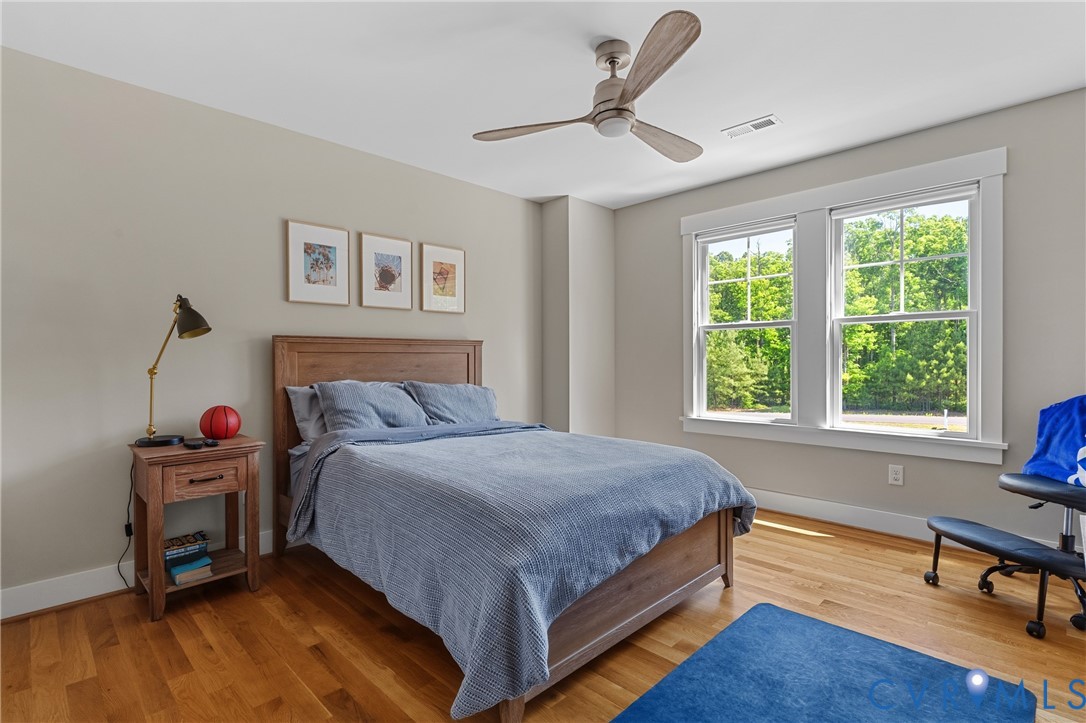 Hardwood flooring, painted walls, ceiling fan, and large windows with white trim