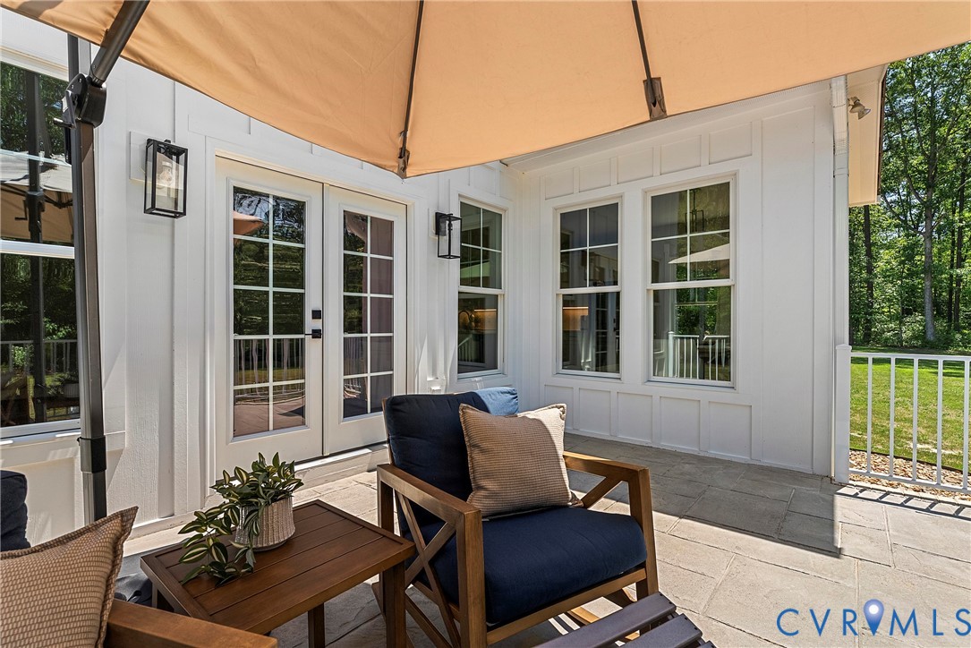 Exterior patio with board and batten siding, double French doors, large windows, and a stone paver surface