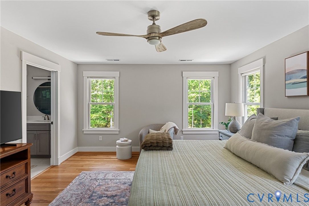 Hardwood flooring, two windows with white trim, and a ceiling fan with integrated lighting