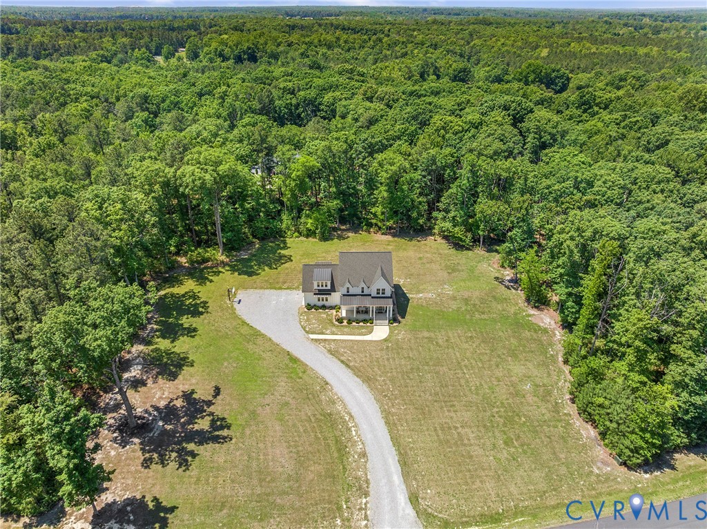 Expansive lot with a gravel driveway, surrounded by mature trees