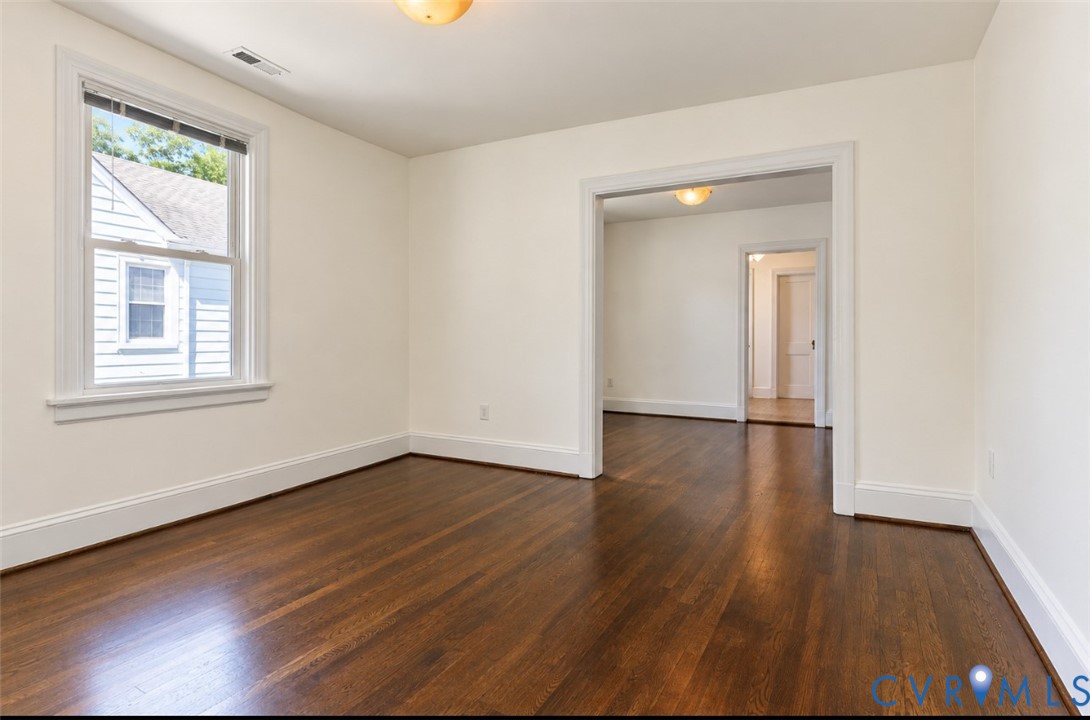 Rich wood-finish flooring, white trim, and a window with natural light