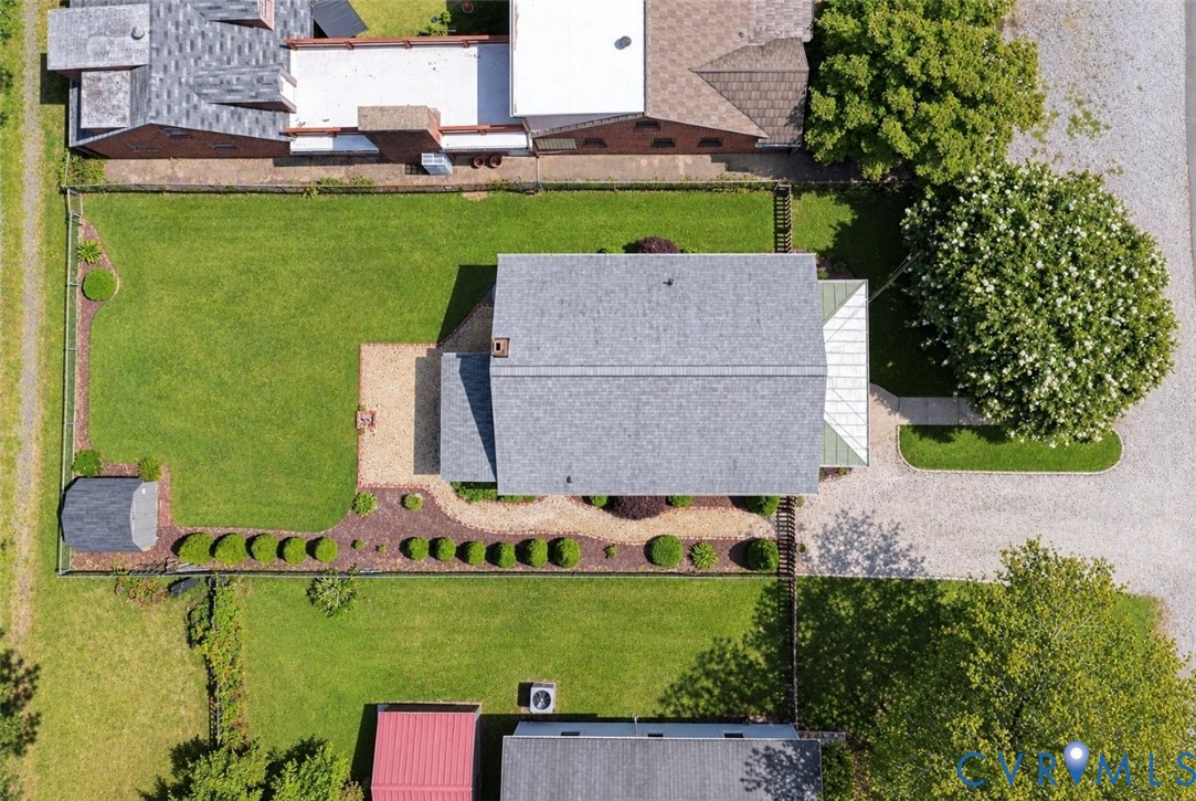 Manicured lawn with gravel patio, established landscaping, and detached shed