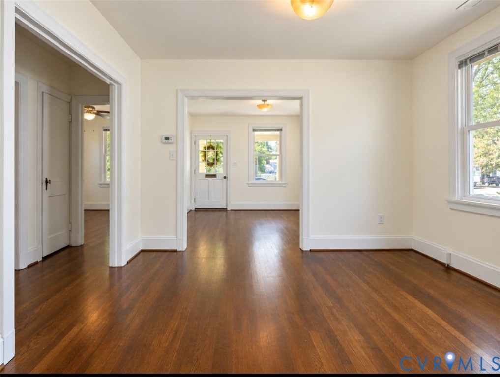 Hardwood flooring throughout, white trim, recessed doorways, and a prominent window