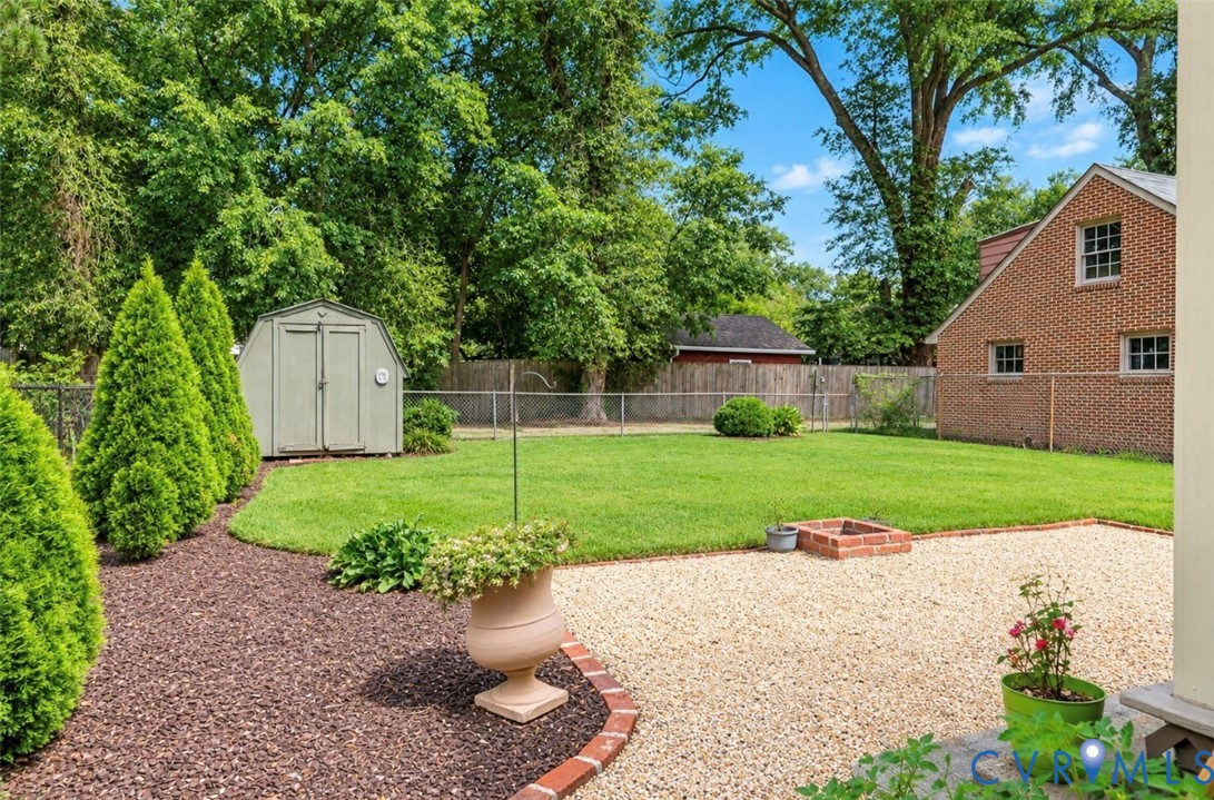 Expansive backyard featuring a gravel patio, a brick fire pit, and a lush green lawn