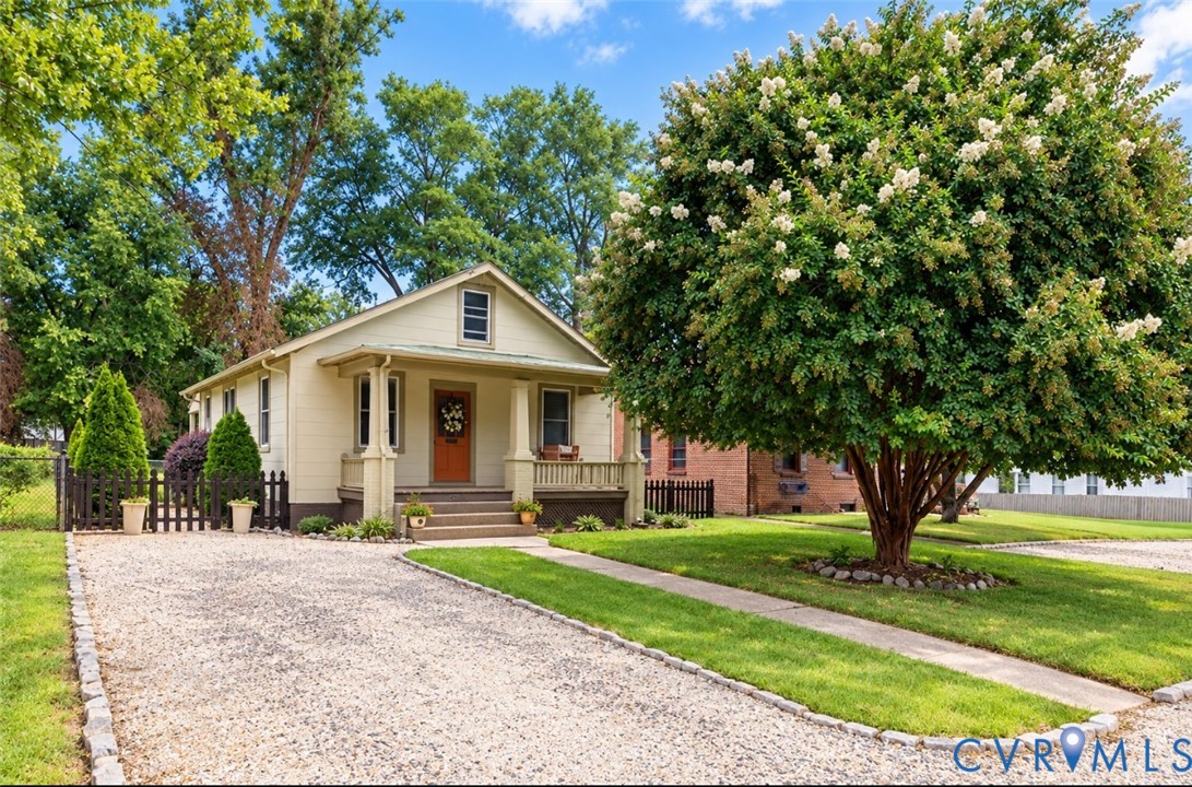 Light-toned exterior, covered porch, green metal accent roof, with an apricot colored front door and matching swing. Stunning 34 year old Crpe Myrtle! Light-toned exterior, covered porch, green metal accent roof, with an apricot colored front door and matching swing. Stunning 34 year old Crpe Myrtle!